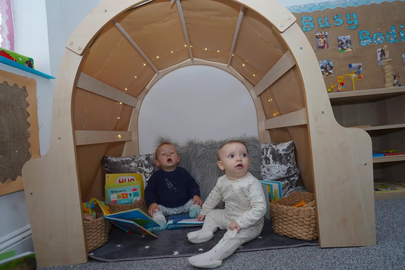 Two babies in the wooden reading arch with fairy lights at Blue Nest Borehamwood