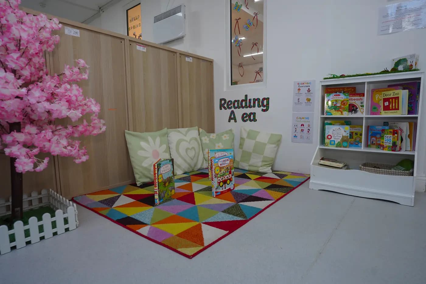 Spring reading area with pink cherry-blossom tree and triangle rug at Blue Nest Borehamwood