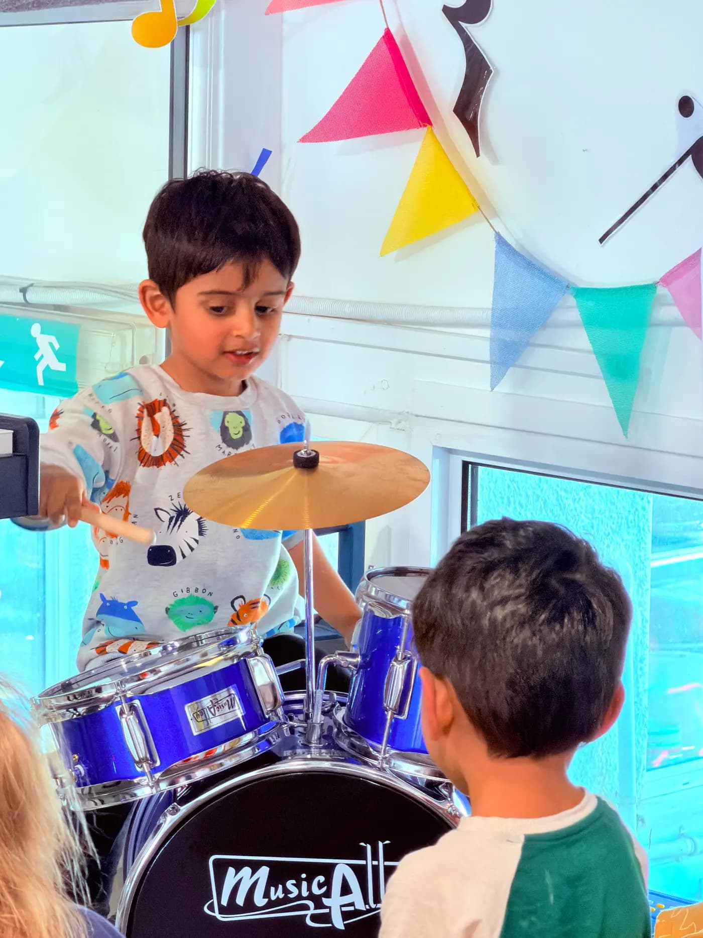 Child playing a drum kit during a music session at Blue Nest Montessori Harrow
