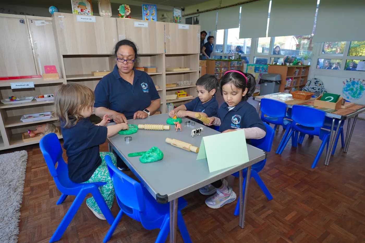 Practical-life dough activity with a teacher and three children at Blue Nest Pinner