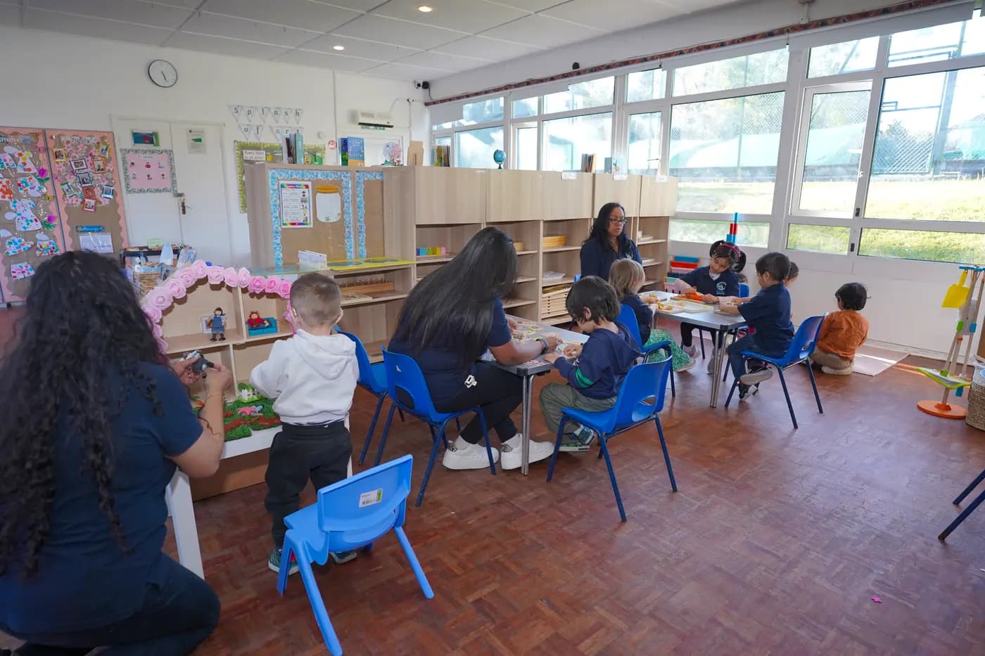 A busy Montessori classroom with children at independent learning stations at Blue Nest Pinner