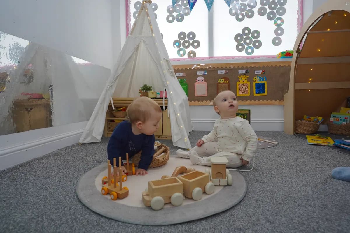 Two babies on the rug by the fairy-light teepee at Blue Nest Borehamwood