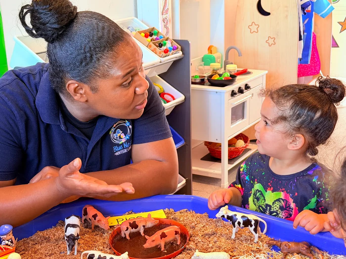 Blue Nest Montessori Harrow educator engaging with a young child at a farm-animal sensory tray