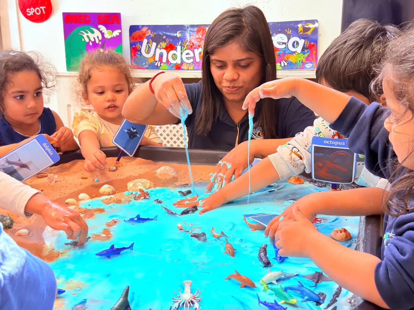 Children and teacher exploring an ocean sensory bin at Blue Nest Harrow