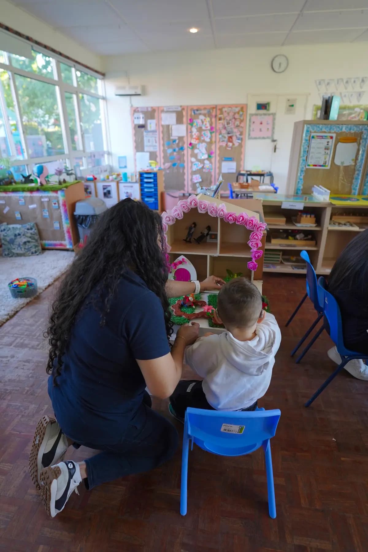 Teacher and child exploring a Montessori dollhouse activity at Blue Nest Pinner